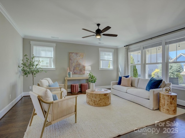 living room featuring dark wood-style flooring, visible vents, baseboards, a ceiling fan, and crown molding