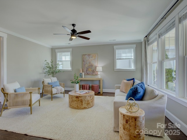 living area with ornamental molding, baseboards, and a ceiling fan