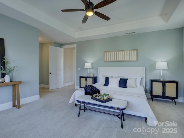 carpeted bedroom featuring ceiling fan, a tray ceiling, visible vents, and baseboards