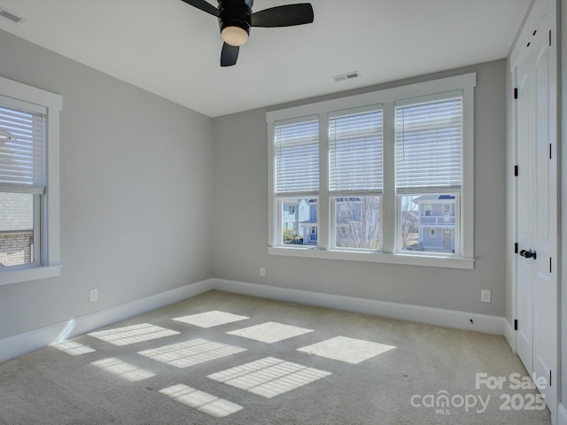 unfurnished room featuring light colored carpet, visible vents, ceiling fan, and baseboards