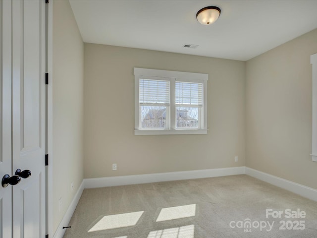 spare room with light colored carpet, visible vents, and baseboards