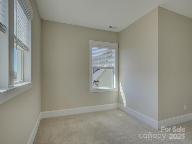 spare room featuring carpet, visible vents, and baseboards