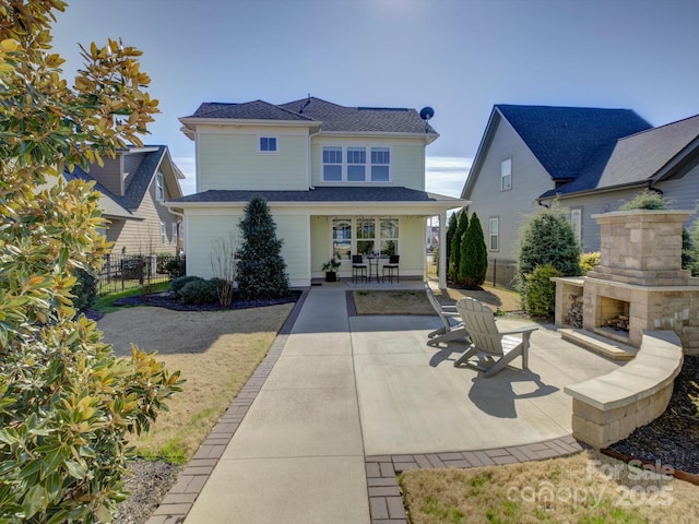 back of property with a patio, an outdoor stone fireplace, and fence