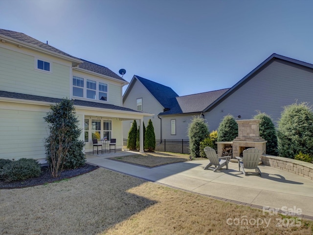 back of house with fence, an outdoor stone fireplace, and a patio