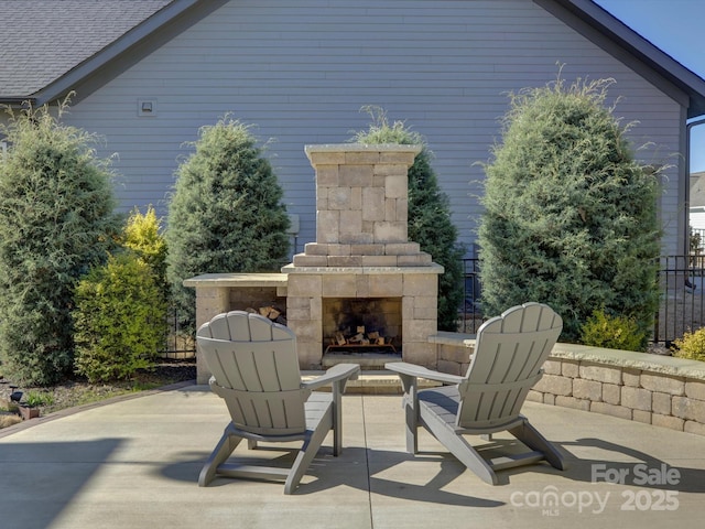 view of patio featuring an outdoor stone fireplace and fence