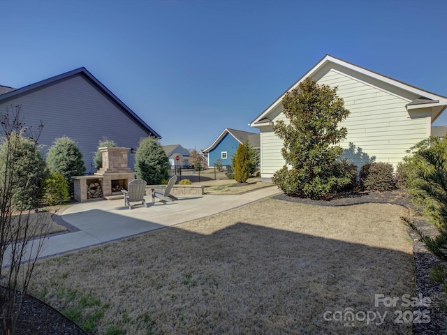 view of yard featuring a patio area, fence, and exterior fireplace