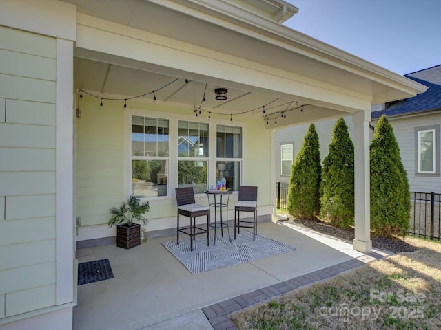 view of patio featuring a porch and fence