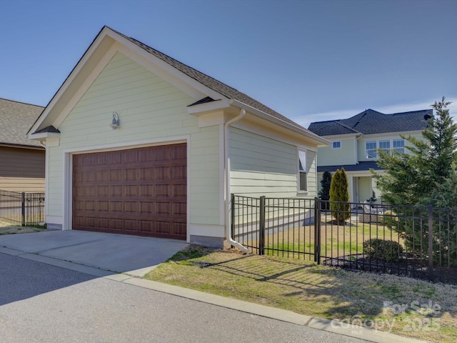 garage featuring fence and concrete driveway