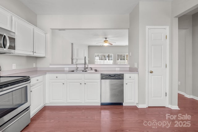 kitchen featuring white cabinets, dark wood-style floors, appliances with stainless steel finishes, light countertops, and a sink