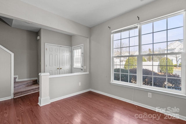 unfurnished room featuring stairs, baseboards, and dark wood-style flooring