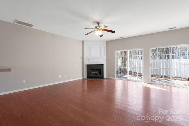 unfurnished living room with ceiling fan, a fireplace, wood finished floors, and visible vents