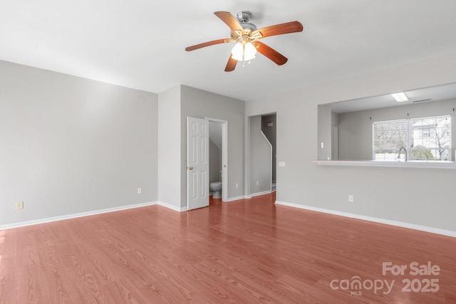 spare room featuring a sink, ceiling fan, baseboards, and wood finished floors