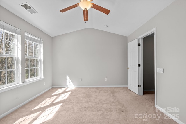 spare room with a ceiling fan, visible vents, vaulted ceiling, baseboards, and carpet