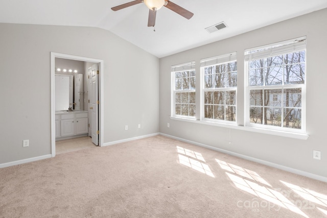 unfurnished bedroom with baseboards, visible vents, light colored carpet, ensuite bath, and vaulted ceiling