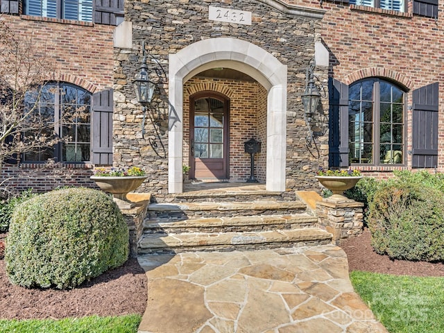 view of exterior entry featuring stone siding and brick siding