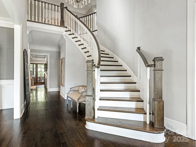 staircase featuring a high ceiling, ornamental molding, and wood finished floors