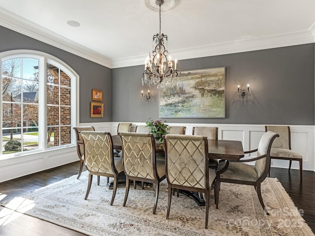 dining room featuring wainscoting, ornamental molding, wood finished floors, a decorative wall, and a notable chandelier