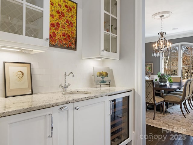 bar featuring beverage cooler, tasteful backsplash, ornamental molding, pendant lighting, and a sink