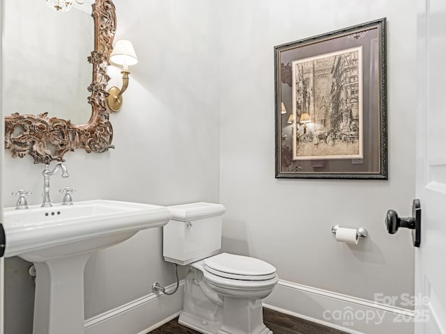 bathroom with wood finished floors, toilet, and baseboards