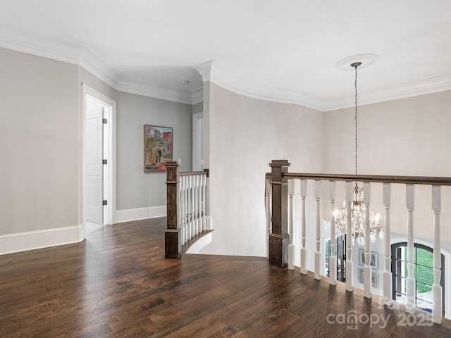 corridor featuring a notable chandelier, ornamental molding, wood finished floors, and an upstairs landing