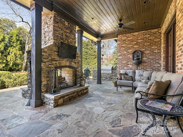 view of patio / terrace with ceiling fan, an outdoor living space with a fireplace, grilling area, and an outdoor kitchen