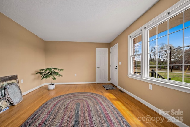 unfurnished room with baseboards, visible vents, a textured ceiling, and wood finished floors