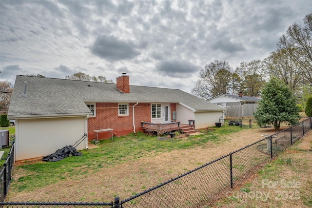 back of house with a lawn, a chimney, a fenced backyard, and roof with shingles