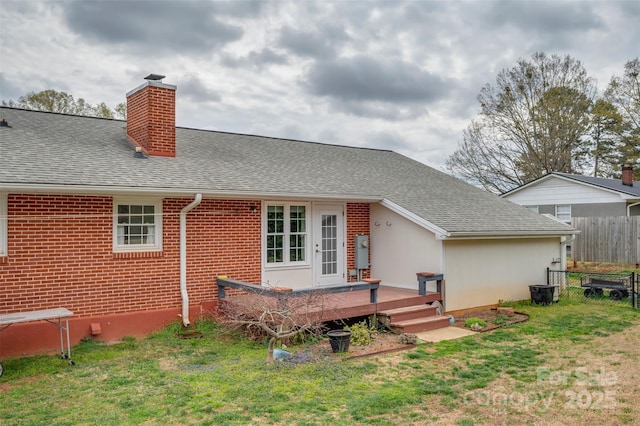 back of house featuring a wooden deck, a shingled roof, fence, and a lawn