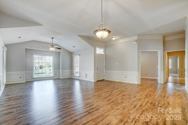 unfurnished living room with light wood-type flooring, ceiling fan, vaulted ceiling, and a decorative wall