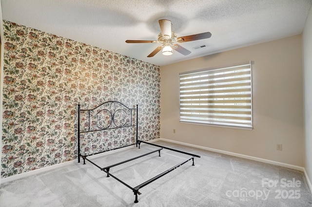 unfurnished bedroom featuring light colored carpet, visible vents, and a textured ceiling