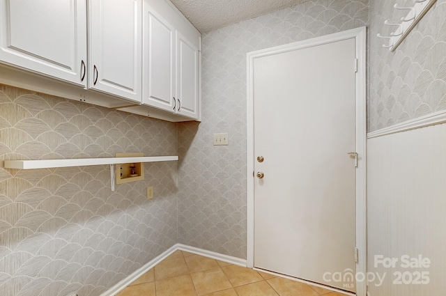 washroom featuring washer hookup, light tile patterned floors, cabinet space, a textured ceiling, and wallpapered walls