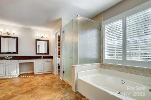 bathroom with double vanity, a stall shower, a sink, a textured ceiling, and a bath