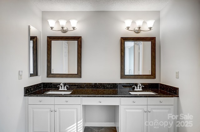 full bathroom with a textured ceiling, double vanity, and a sink