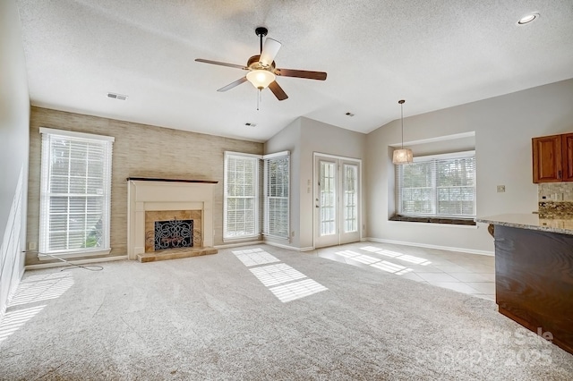 unfurnished living room with visible vents, light carpet, a textured ceiling, and light tile patterned flooring