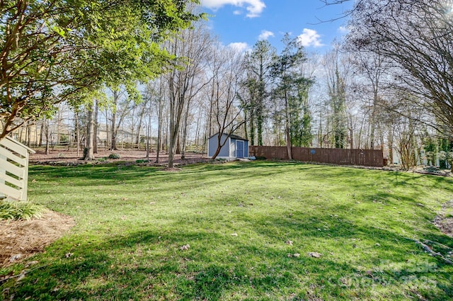 view of yard featuring a shed, fence, and an outdoor structure