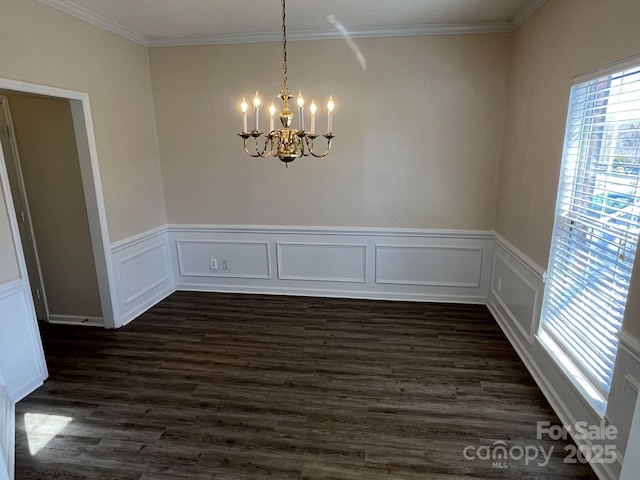 empty room featuring ornamental molding, dark wood-type flooring, and an inviting chandelier