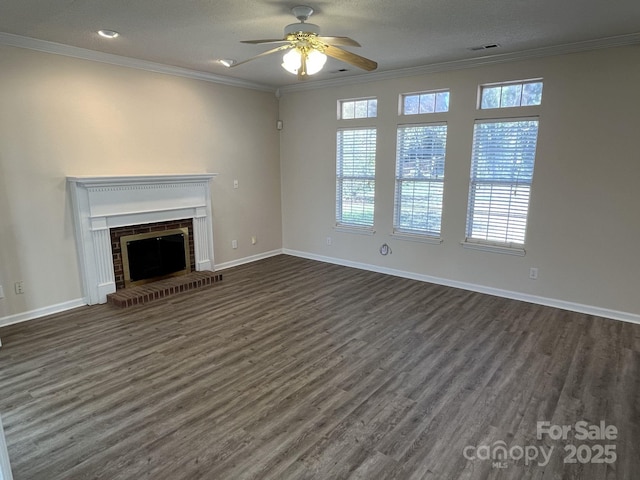 unfurnished living room with a brick fireplace, dark wood-style flooring, a wealth of natural light, and crown molding