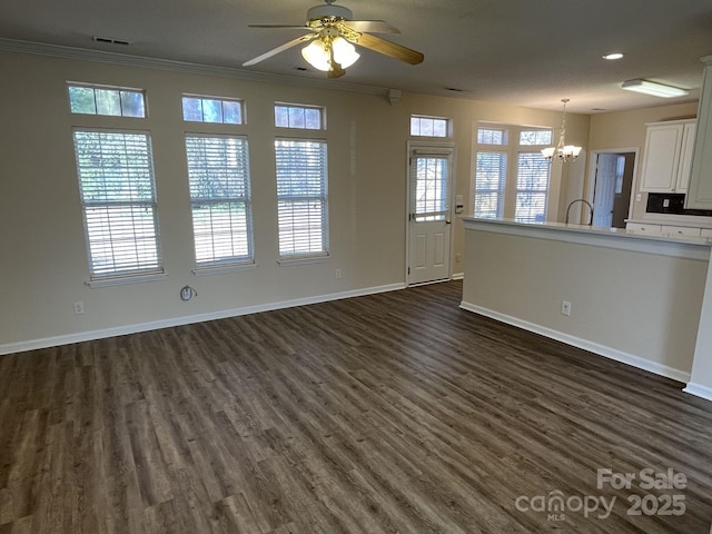 unfurnished living room featuring visible vents, baseboards, dark wood-style flooring, crown molding, and ceiling fan with notable chandelier