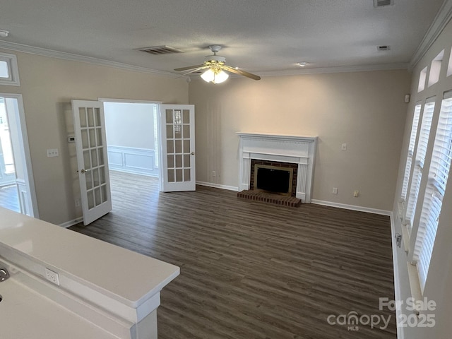 unfurnished living room with a brick fireplace, visible vents, crown molding, and french doors