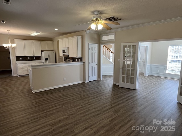 kitchen with white appliances, visible vents, white cabinetry, light countertops, and decorative light fixtures