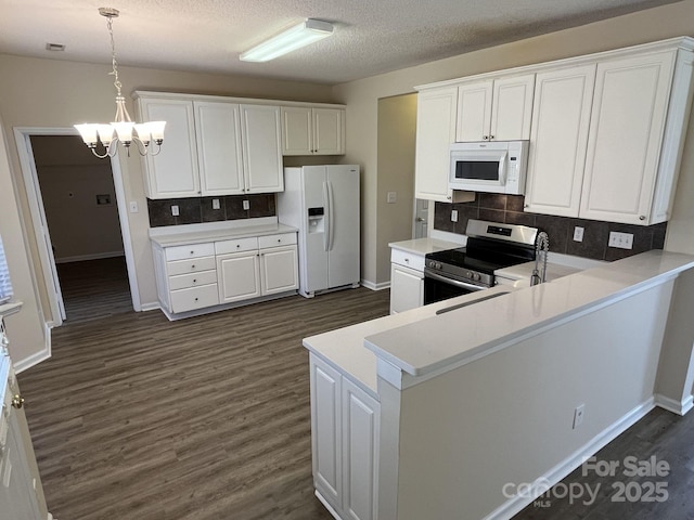 kitchen with decorative light fixtures, light countertops, white cabinets, white appliances, and a peninsula