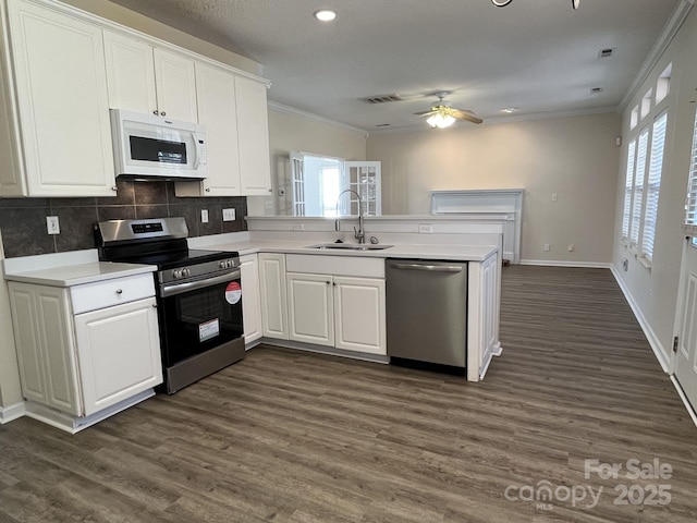 kitchen with stainless steel appliances, a peninsula, light countertops, and white cabinetry