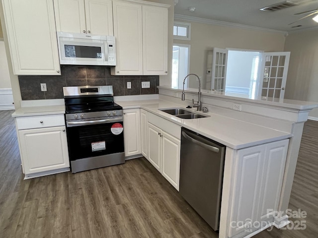 kitchen featuring stainless steel appliances, light countertops, a sink, and a peninsula