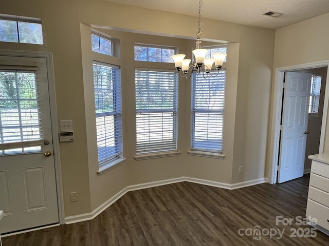 interior space featuring visible vents, dark wood-type flooring, a textured ceiling, a chandelier, and baseboards