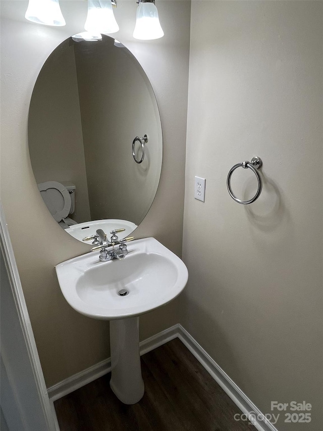 half bathroom featuring toilet, baseboards, and wood finished floors