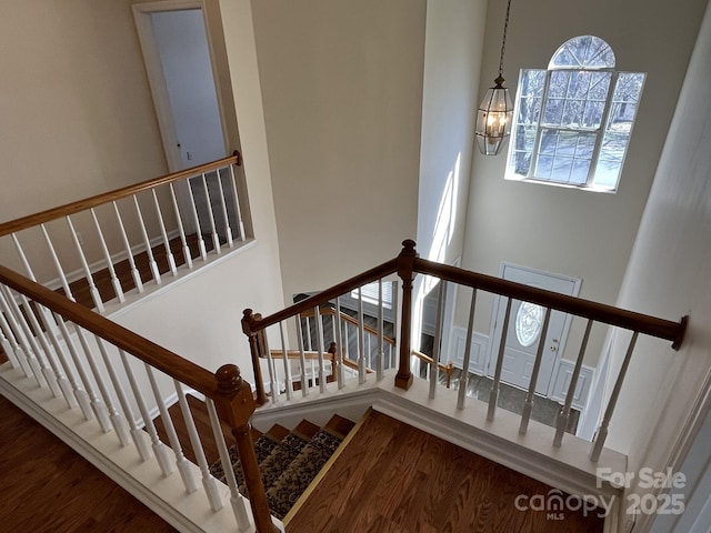 staircase with wood finished floors and a notable chandelier