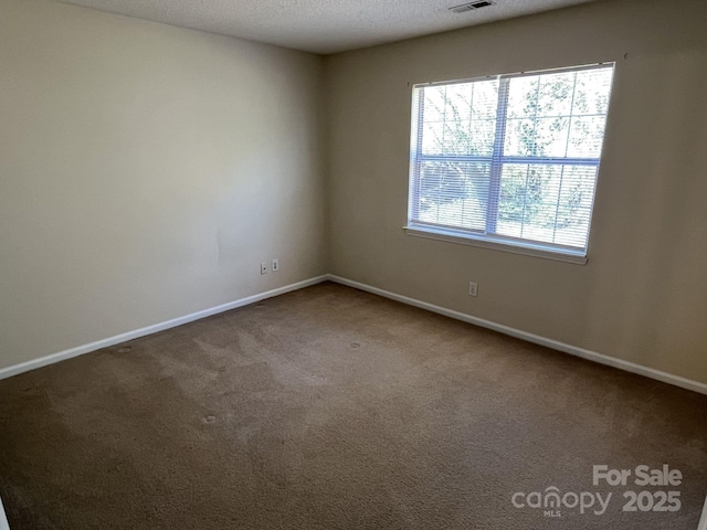 unfurnished room featuring carpet floors, visible vents, and baseboards