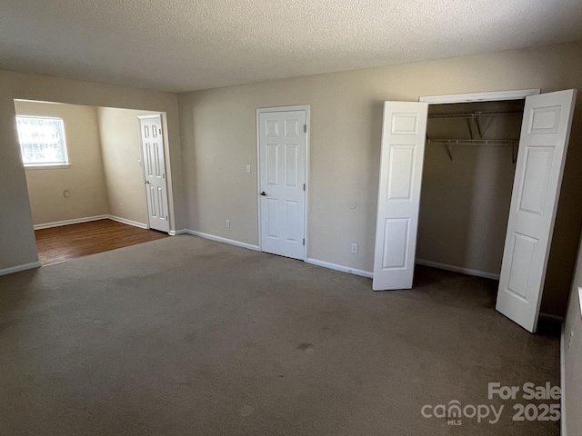 unfurnished bedroom with a textured ceiling, a closet, carpet, and baseboards