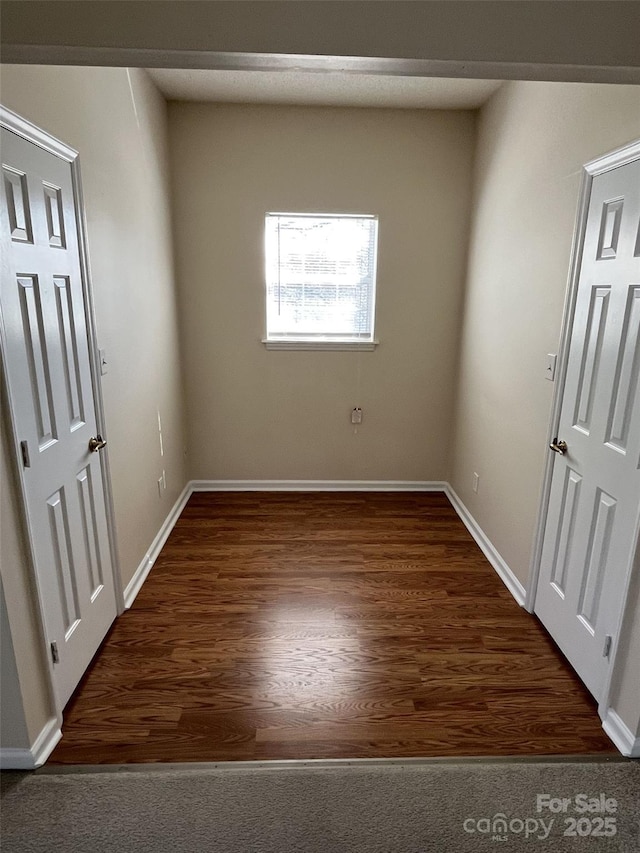 spare room featuring dark wood finished floors and baseboards