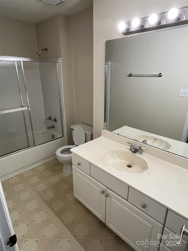 full bathroom with bath / shower combo with glass door, vanity, toilet, and tile patterned floors